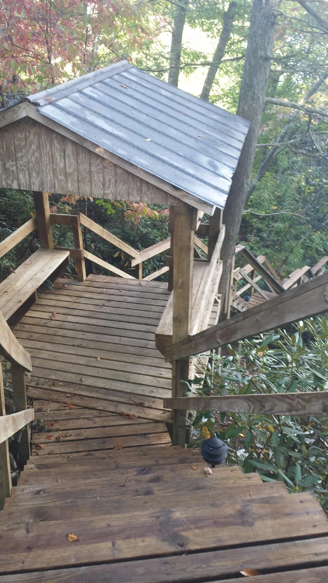 Metal roofed shelter over wooden steps on a wooded walkway — Skylight Repair & Installation work by our crew in Church Hill
