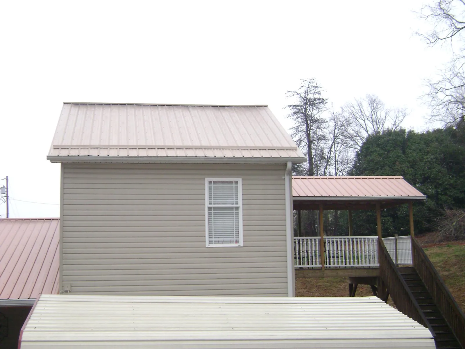 Tan metal roofs on a two story addition and attached porch, from a Roof Replacement job in Church Hill